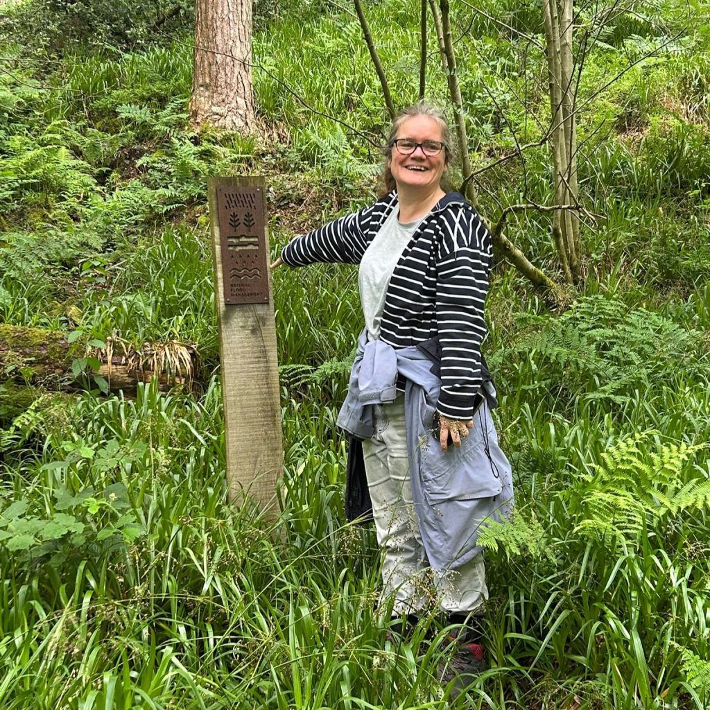 Woman stood in a wood next to a tree